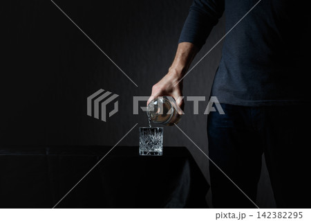 Man pouring strong alcoholic drink in glass. 142382295