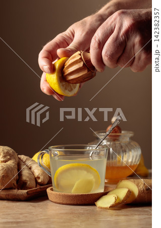 Ginger tea with lemon and honey on a brown ceramic table. 142382357
