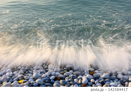 A dynamic coastal scene with a breaking wave on pebble beach A dynamic coastal scene with a breaking wave on pebble beach 142384417