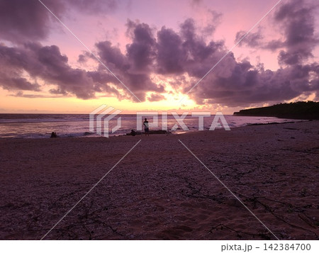 夕焼けに染まる海辺と砂浜のシルエット 142384700