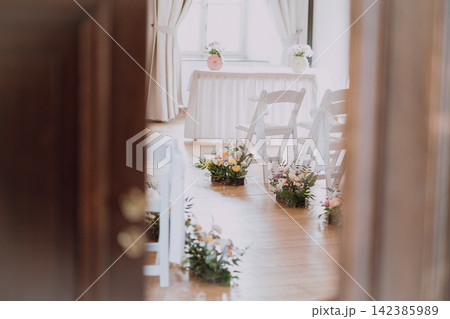 Beautiful wedding venue decor with flower decorated guest chairs and romantic details Beautiful wedding venue decor with flower decorated guest chairs and romantic details 142385989