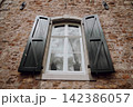 Ancient castle window with wooden shutters, European historic architecture. Medieval castle interior window with traditional shutters and rustic details 142386057