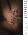 Tender Sibling Bond Between Young Child and Newborn Baby, Little Hands Holding Together, Symbol of Love, Family, New Life and Birth, Sepia Close-Up 142386061