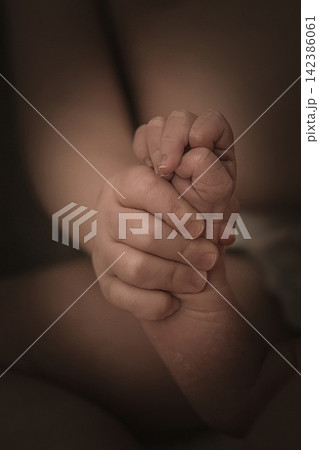 Tender Sibling Bond Between Young Child and Newborn Baby, Little Hands Holding Together, Symbol of Love, Family, New Life and Birth, Sepia Close-Up 142386061