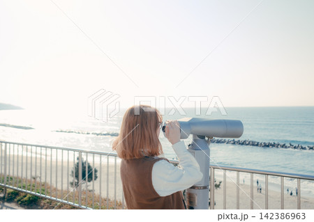 展望台の望遠鏡から海を眺める若い女性 展望台の望遠鏡から海を眺める若い女性 142386963