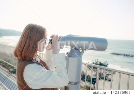 展望台の望遠鏡から海を眺める若い女性 展望台の望遠鏡から海を眺める若い女性 142386965