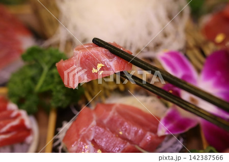 Sashimi Slice Held by Chopsticks in Japanese Cuisine Sashimi Slice Held by Chopsticks in Japanese Cuisine 142387566