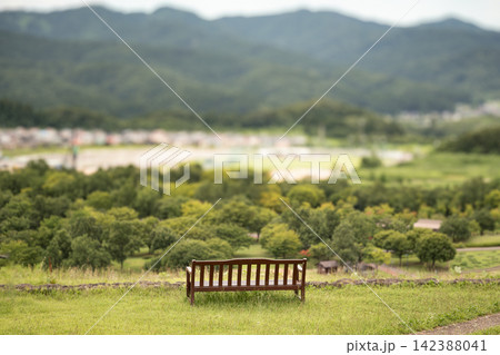 丘の上の木製ベンチから見下ろす街並みと山並みの絶景 丘の上の木製ベンチから見下ろす街並みと山並みの絶景 142388041