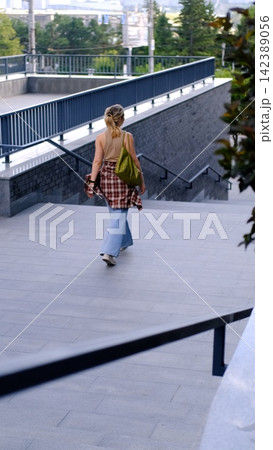 Young Woman Walking Away Through Modern Urban Plaza, Casual Street Fashion, Independent Lifestyle, City Mobility and Everyday Life Young Woman Walking Away Through Modern Urban Plaza, Casual Street Fashion, Independent Lifestyle, City Mobility and Everyday Life 142389056