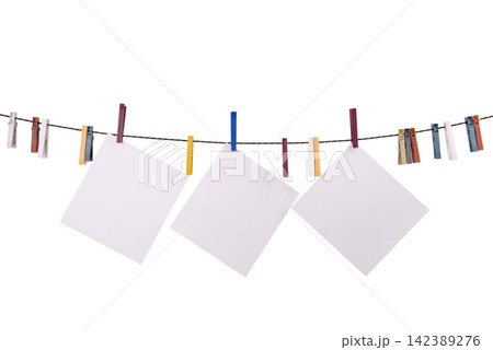 Three blank white squares of paper are hanging on a clothesline with colorful clothespins Three blank white squares of paper are hanging on a clothesline with colorful clothespins 142389276