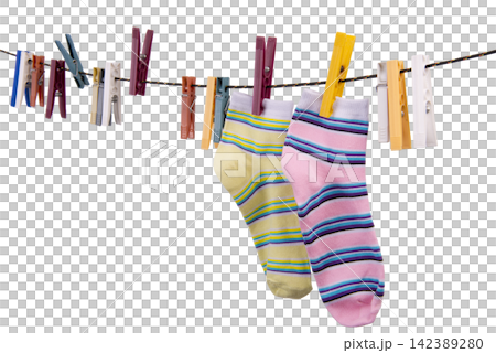Two striped socks, one yellow and one pink, hang on a clothesline clipped by various clothespins. Two striped socks, one yellow and one pink, hang on a clothesline clipped by various clothespins. 142389280