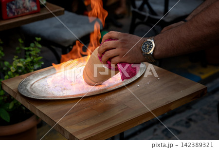 Istanbul,turkey,august 2, 2025. Hands breaking open a flaming clay testi kebab on a metal tray at an istanbul restaurant, dramatic traditional dining ritual Istanbul,turkey,august 2, 2025. Hands breaking open a flaming clay testi kebab on a metal tray at an istanbul restaurant, dramatic traditional dining ritual 142389321