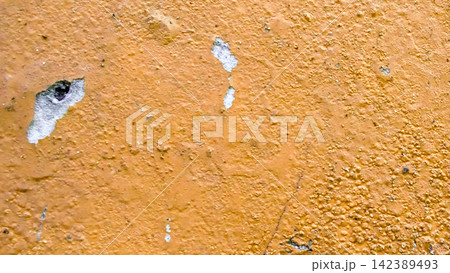 Peeling ocher yellow paint on a weathered wall texture 142389493