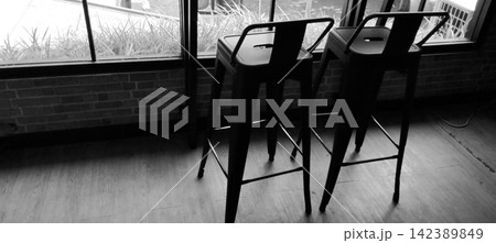 Black and white industrial style metal bar stools near the window in a cafe interior. 142389849