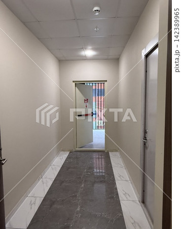 Empty hallway with closed door and fire exit sign, tiled floor, suitable for background 142389965