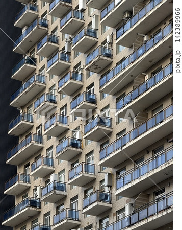 Urban high-rise building facade with numerous balconies, showcasing modern city architecture. Urban high-rise building facade with numerous balconies, showcasing modern city architecture. 142389966
