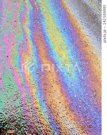 A leaked Car Oil Petrol in The Rain on a Tarmac Road Metallic Rainbow Gasoline A leaked Car Oil Petrol in The Rain on a Tarmac Road Metallic Rainbow Gasoline 142389995
