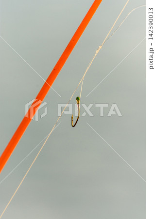 A detailed close-up photograph of a fly fishing hook and line against a muted 142390013