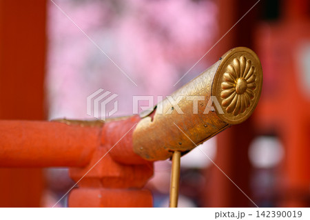 A detailed golden cylindrical item set against a softly blurred background, likely part of a traditional Japanese shrine or ceremonial practice 142390019