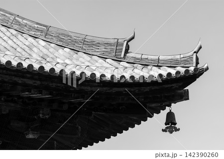 A detailed black and white photograph showcasing an intricate, ornate Chinese roof with repeating patterns of gently arched tiles supported by dark wooden beams A detailed black and white photograph showcasing an intricate, ornate Chinese roof with repeating patterns of gently arched tiles supported by dark wooden beams 142390260