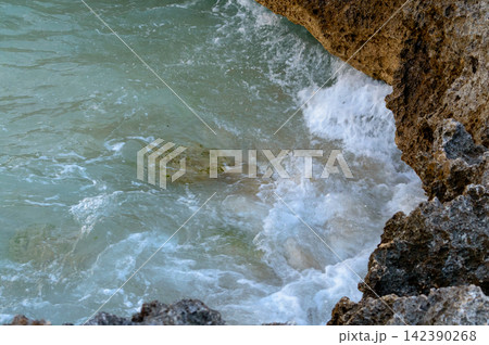 A dynamic coastal view from above, showing powerful waves crashing against rugged rock formations 142390268