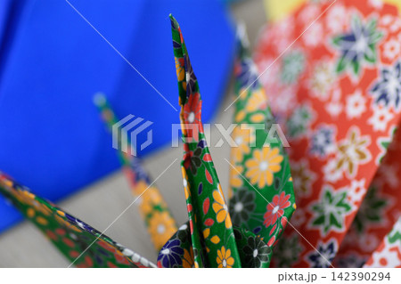 Close-up photograph of intricately folded traditional Japanese paper cranes with a deep blue backdrop 142390294