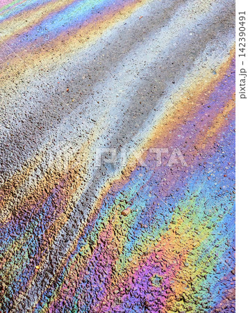 A leaked Car Oil Petrol in The Rain on a Tarmac Road Metallic Rainbow Gasoline 142390491