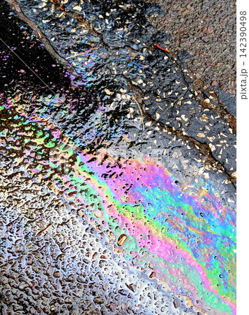 A leaked Car Oil Petrol in The Rain on a Tarmac Road Metallic Rainbow Gasoline A leaked Car Oil Petrol in The Rain on a Tarmac Road Metallic Rainbow Gasoline 142390498