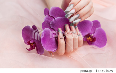 Female hands displaying long creative nail art with orchids Female hands displaying long creative nail art with orchids 142391029