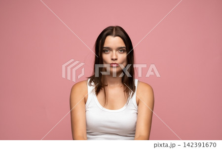 Young woman pouting lips with duck face expression, creating a playful and cheeky attitude posing on a pink background Young woman pouting lips with duck face expression, creating a playful and cheeky attitude posing on a pink background 142391670