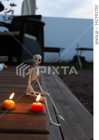 Candlelit Skeleton Prop in Twilight Halloween Scene on Rustic Deck Candlelit Skeleton Prop in Twilight Halloween Scene on Rustic Deck 142391792