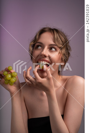 Young woman enjoying fresh green grapes, looking up, promoting healthy eating and natural beauty concept Young woman enjoying fresh green grapes, looking up, promoting healthy eating and natural beauty concept 142391819