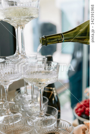 Champagne being poured into crystal glasses at a festive celebration with sparkling wine and romantic atmosphere Champagne being poured into crystal glasses at a festive celebration with sparkling wine and romantic atmosphere 142391968