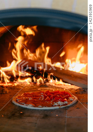 Fresh pizza cooking and baking with bright flames and glowing embers. 142391969