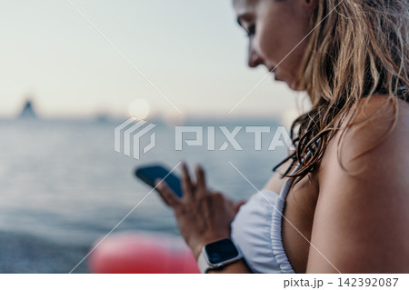 Woman phone sunset young woman uses smartphone by the sea enjoying a serene evening with copy space. 142392087