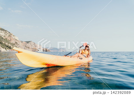 Kayaking Couple Sea Coast Summer Vacation - Couple kayaking on a sunny day on the ocean near a cliff. Kayaking Couple Sea Coast Summer Vacation - Couple kayaking on a sunny day on the ocean near a cliff. 142392089