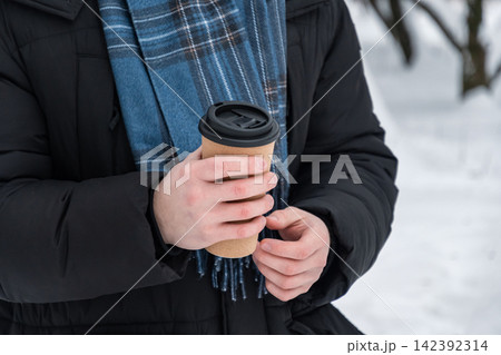 Man holding takeaway coffee cup outdoors in winter 142392314