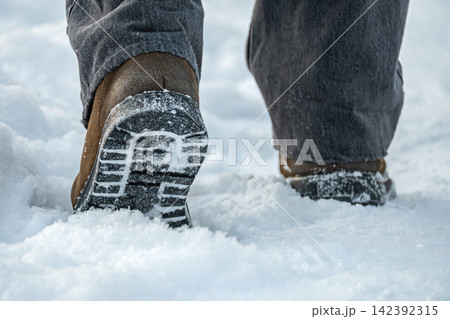 Winter boots walking through deep snow close up 142392315