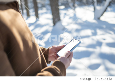 Man using smartphone outdoors in snowy winter park Man using smartphone outdoors in snowy winter park 142392318