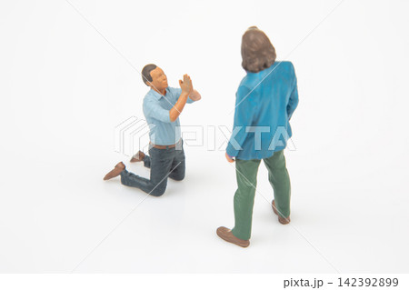 Miniature figures show a scene with one person kneeling and another standing in a simple setup 142392899