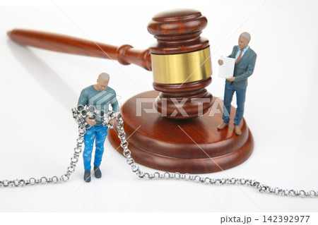 Miniature people with a gavel and chains in a legal setting Miniature people with a gavel and chains in a legal setting 142392977