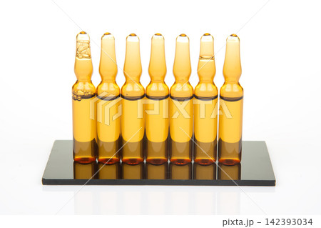 Collection of glass vials arranged on a black base with an empty space at the left side showing clear liquid 142393034