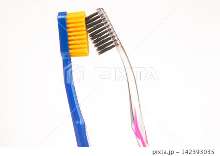 Two toothbrushes in close up view showing different bristle styles and colors in a bright setting Two toothbrushes in close up view showing different bristle styles and colors in a bright setting 142393035