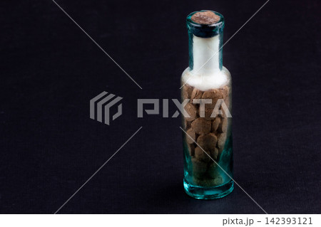 Vintage Glass Bottle with Old Pharmaceutical Tablets on Dark Background Vintage Glass Bottle with Old Pharmaceutical Tablets on Dark Background 142393121