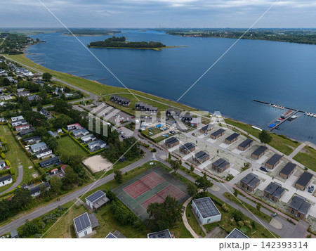 High angle wide horizontal aerial drone photograph of lakeside holiday resort, bungalows, tennis courts, sailing marina, and Lake Veere in Kamperland, Zeeland, Netherlands on cloudy summer day High angle wide horizontal aerial drone photograph of lakeside holiday resort, bungalows, tennis courts, sailing marina, and Lake Veere in Kamperland, Zeeland, Netherlands on cloudy summer day 142393314