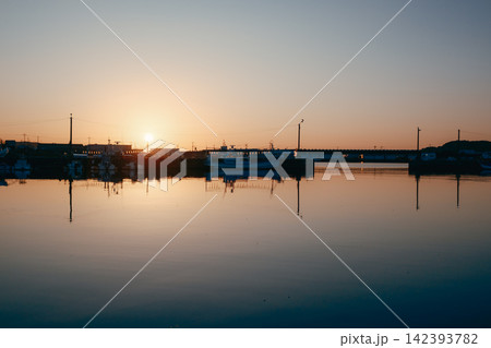 夕日に染まる漁港と水面に映る漁船の夕景 夕日に染まる漁港と水面に映る漁船の夕景 142393782