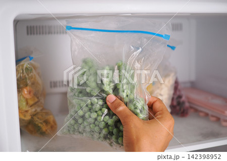 Filling a bag with frozen peas from the freezer 142398952