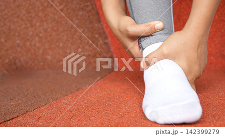 A woman with a leg ache, she is running in the park. 142399279