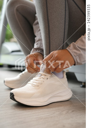 A woman ties her shoelaces ready to run at the gym. 142399335