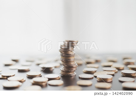 Leaning stack of coins surrounded by scattered money symbolizes financial instability, economic risk, fragile savings, debt pressure, uncertain investment, imbalance, and market volatility. Leaning stack of coins surrounded by scattered money symbolizes financial instability, economic risk, fragile savings, debt pressure, uncertain investment, imbalance, and market volatility. 142402090